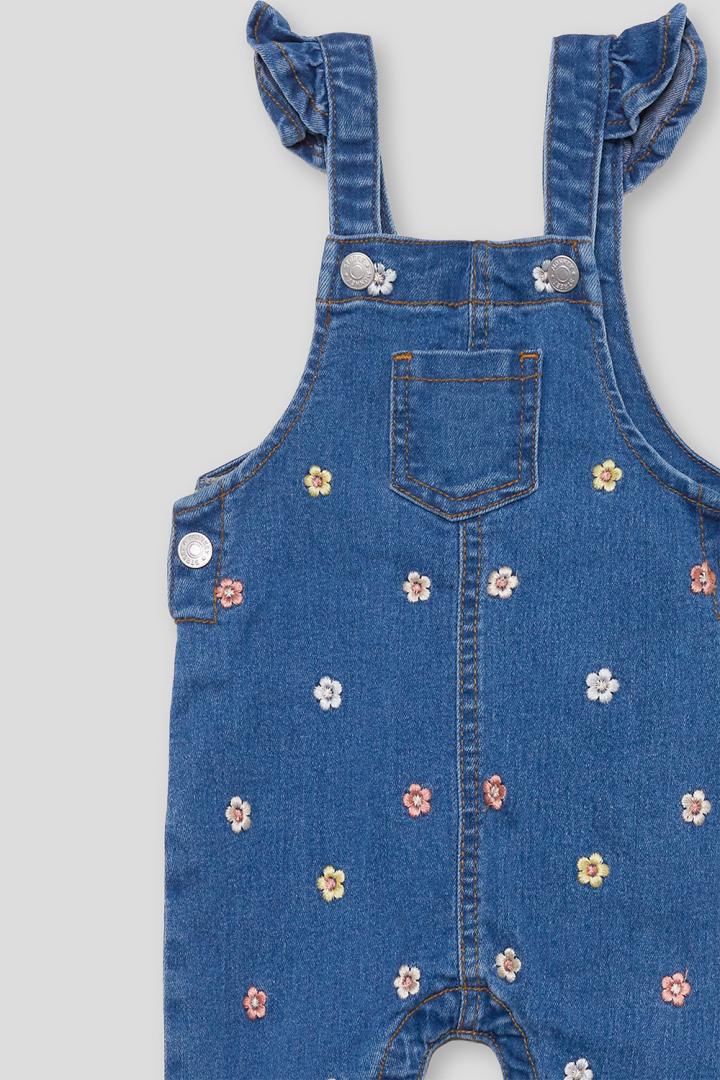 Detalle de bordados florales y volantes del peto vaquero niña